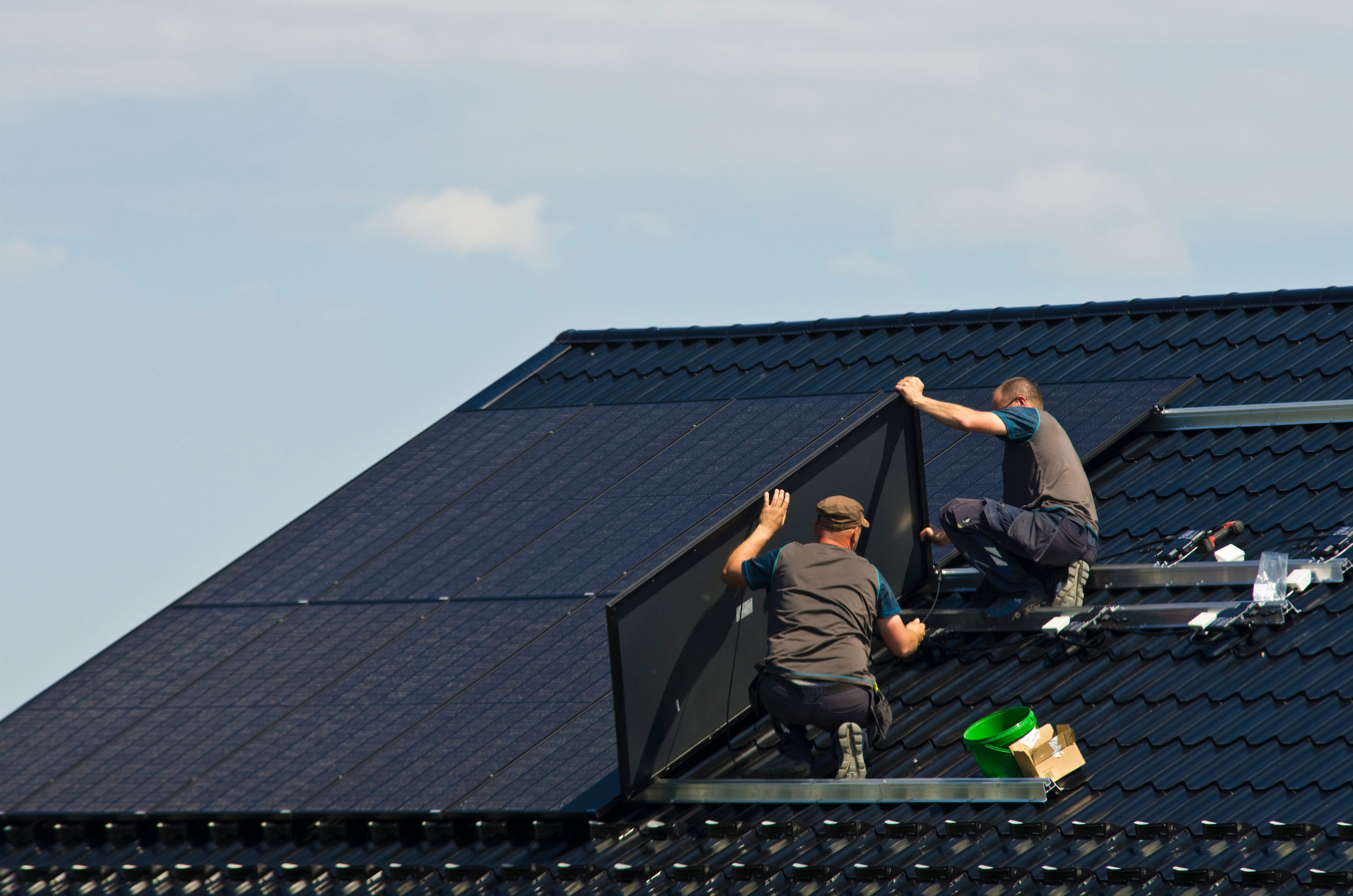 Roofing contractors installing a solar panel on a residential roof