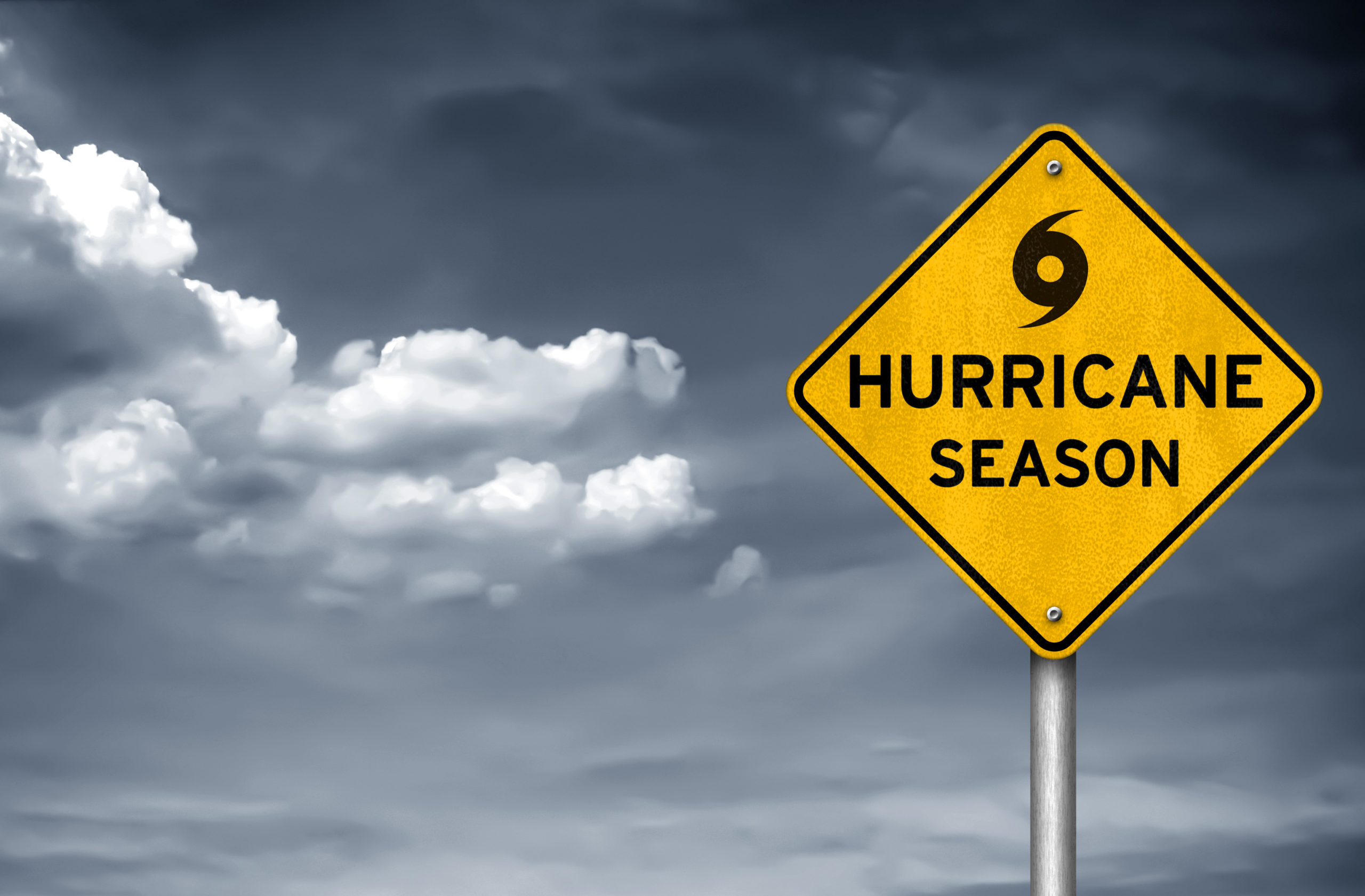 A sign that says "hurricane season" in front of dark, stormy skies