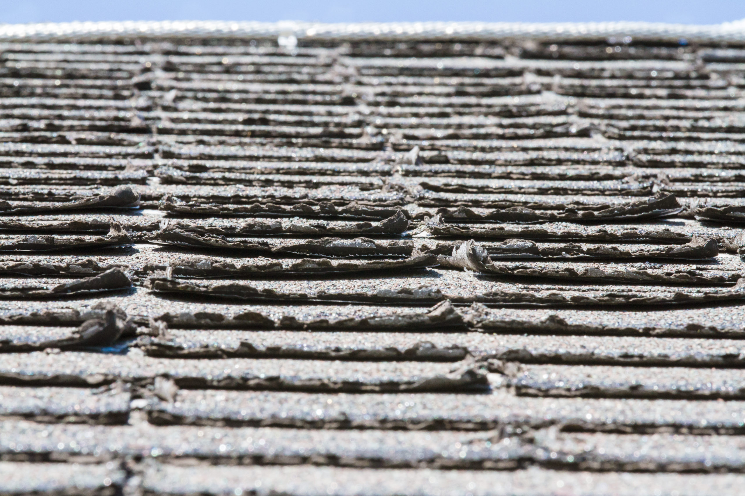 An image of buckling, curling asphalt shingles on a roof