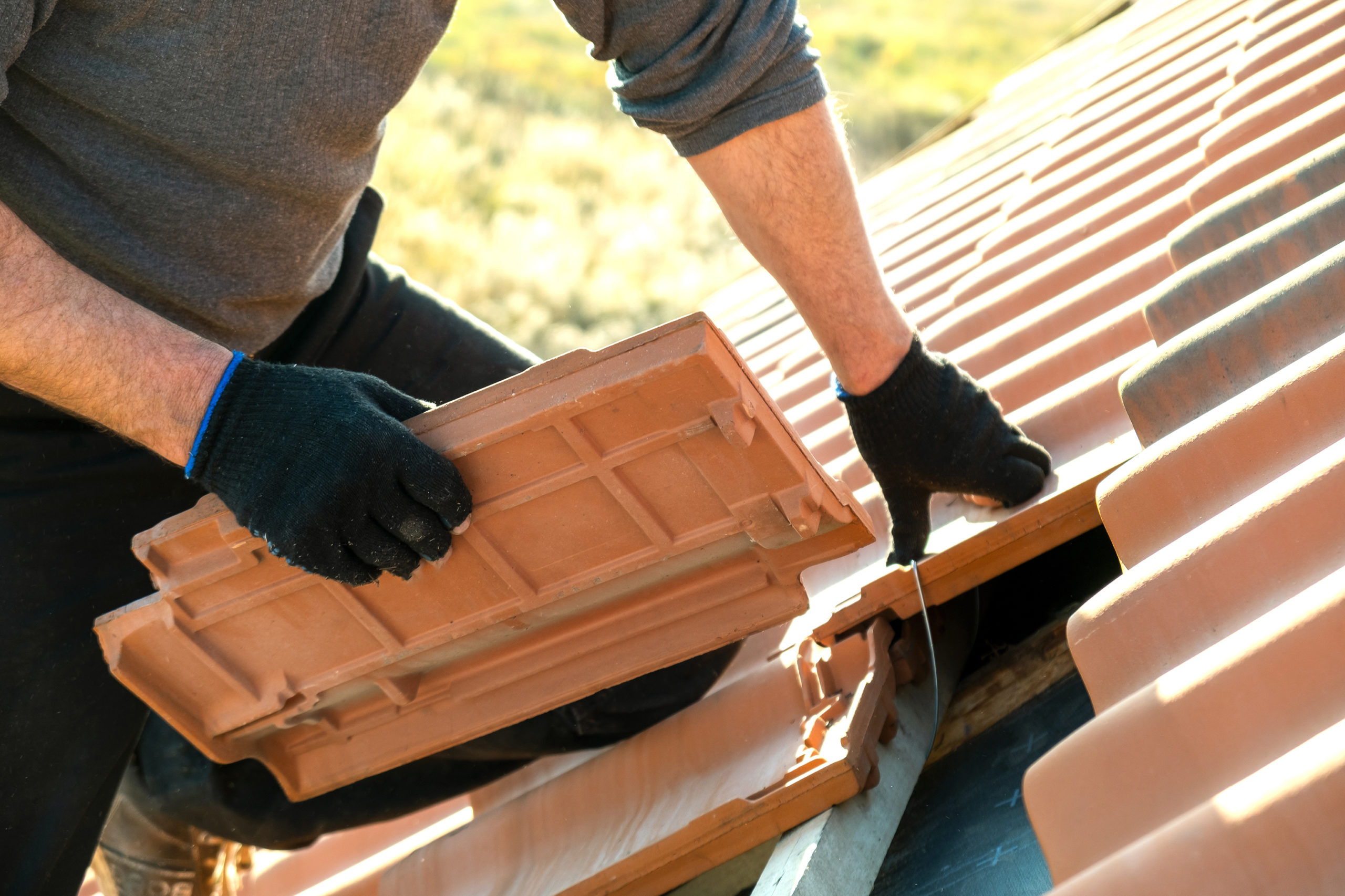 A close-up image of a roofing contractor installing new tiles on a residential roof