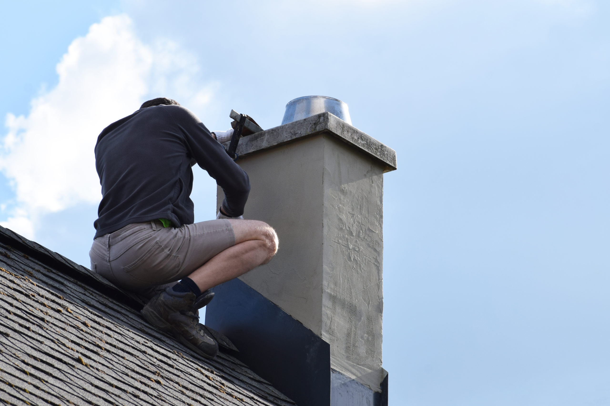A roofing worker repair the flashing around a chimney on a residential home