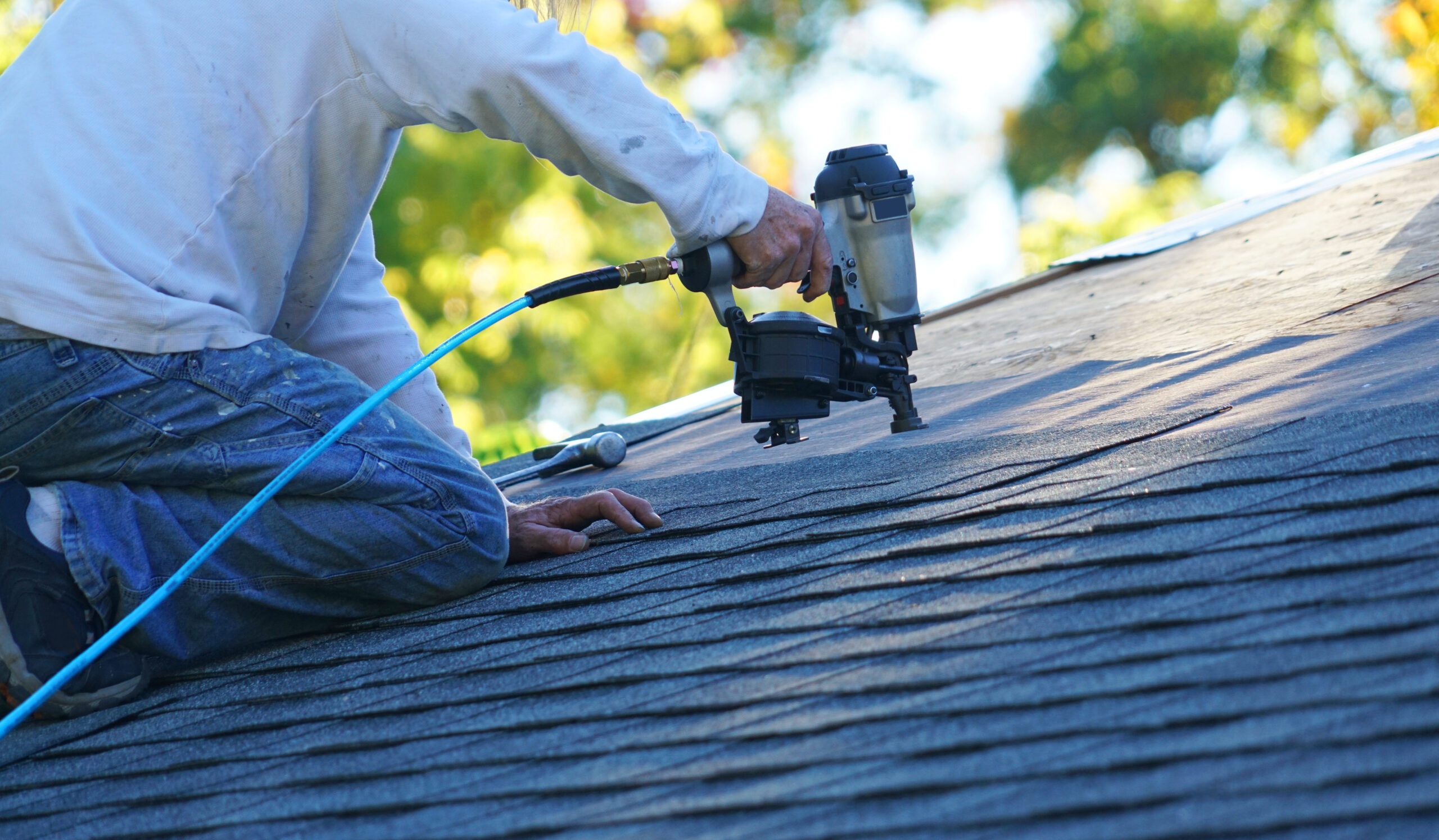 Roofer nailing shingles on a roof during a repair