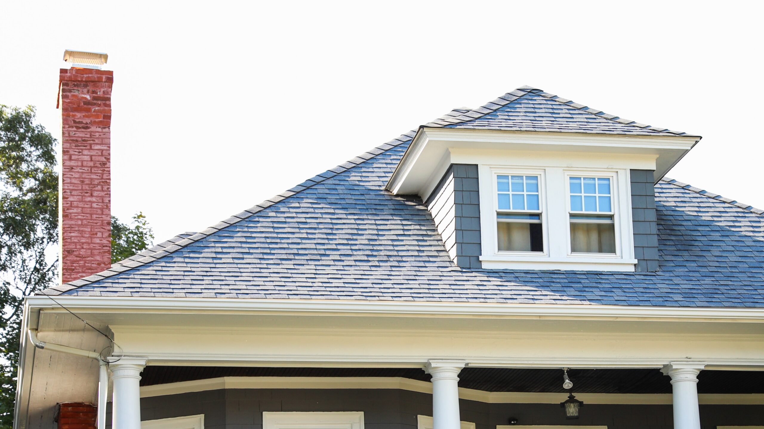 Asphalt shingled roof with window on roof gable and sky view