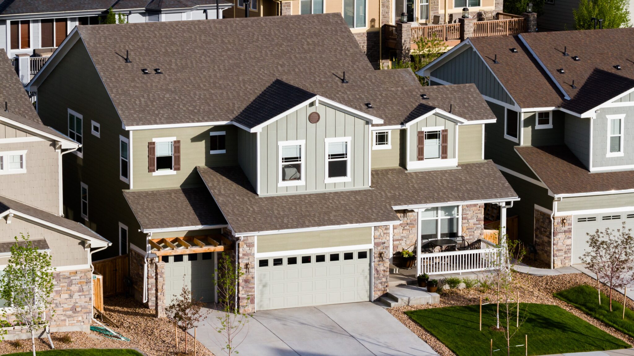 Large aerial view of big home with brown asphalt shingle roofing and different kinds of siding on it