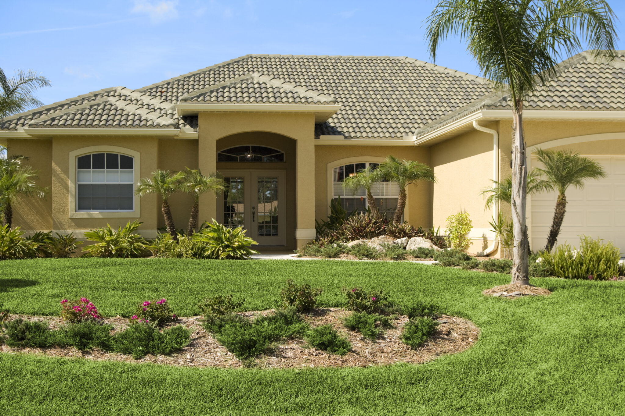 Stucco Florida house with brown tile roof and garden in front