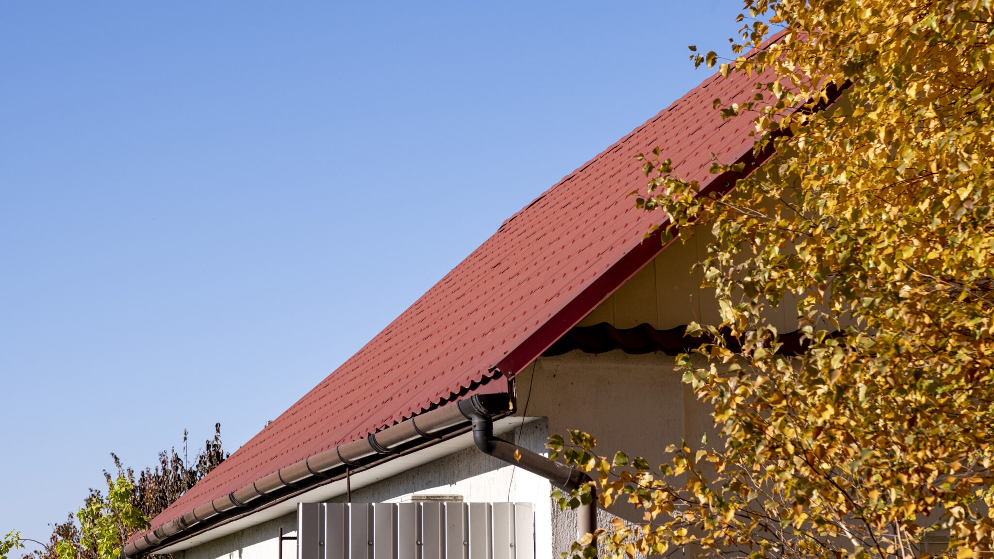Image of a brown metal roof on a brick, two-story house