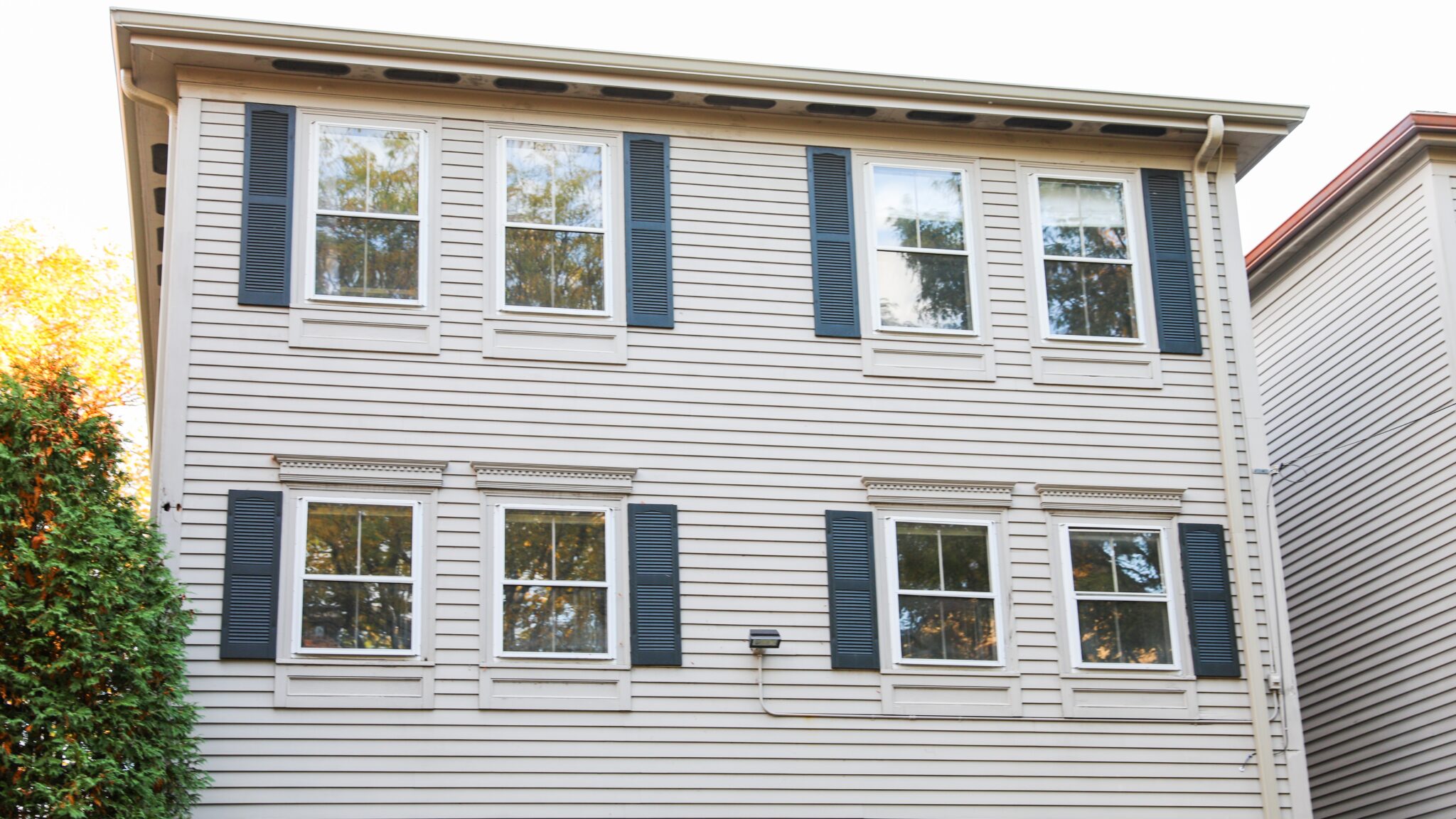 Two-story home with four windows and off-white colored siding