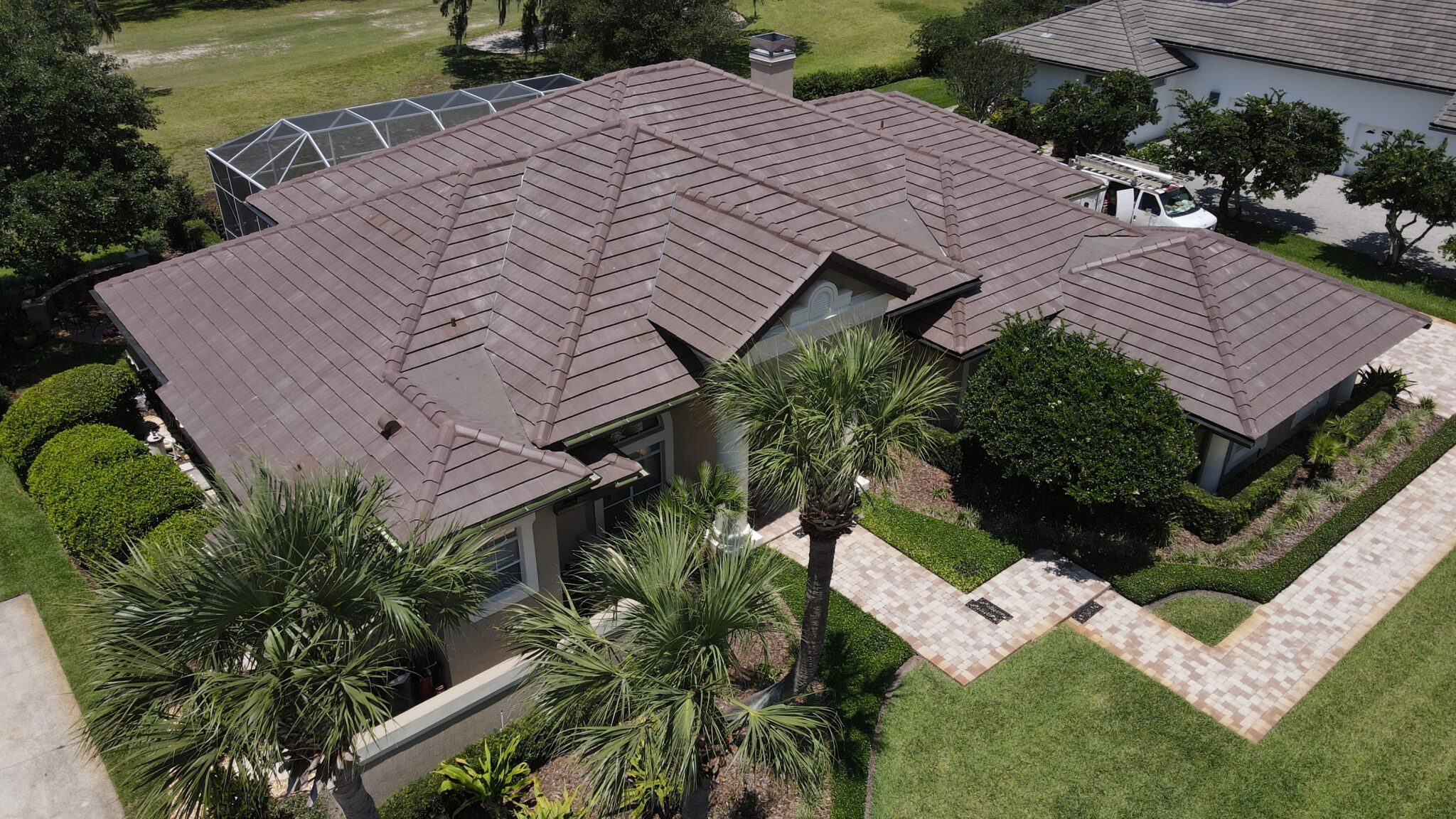 Aerial view of home with large low-sloped brown tile roofing