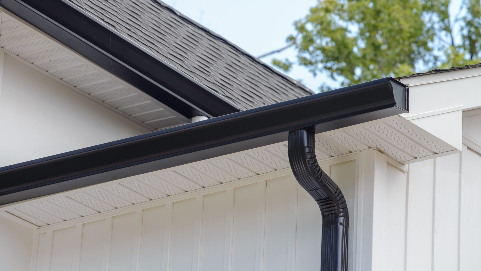 Home corner with dark gutters and new soffit and fascia installation