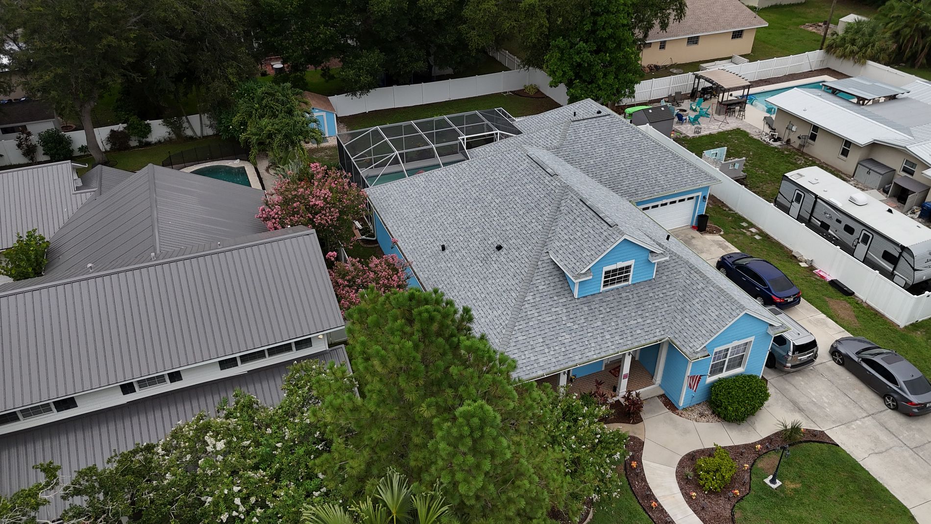 This image features a pretty blue house with an asphalt-shingled roof.