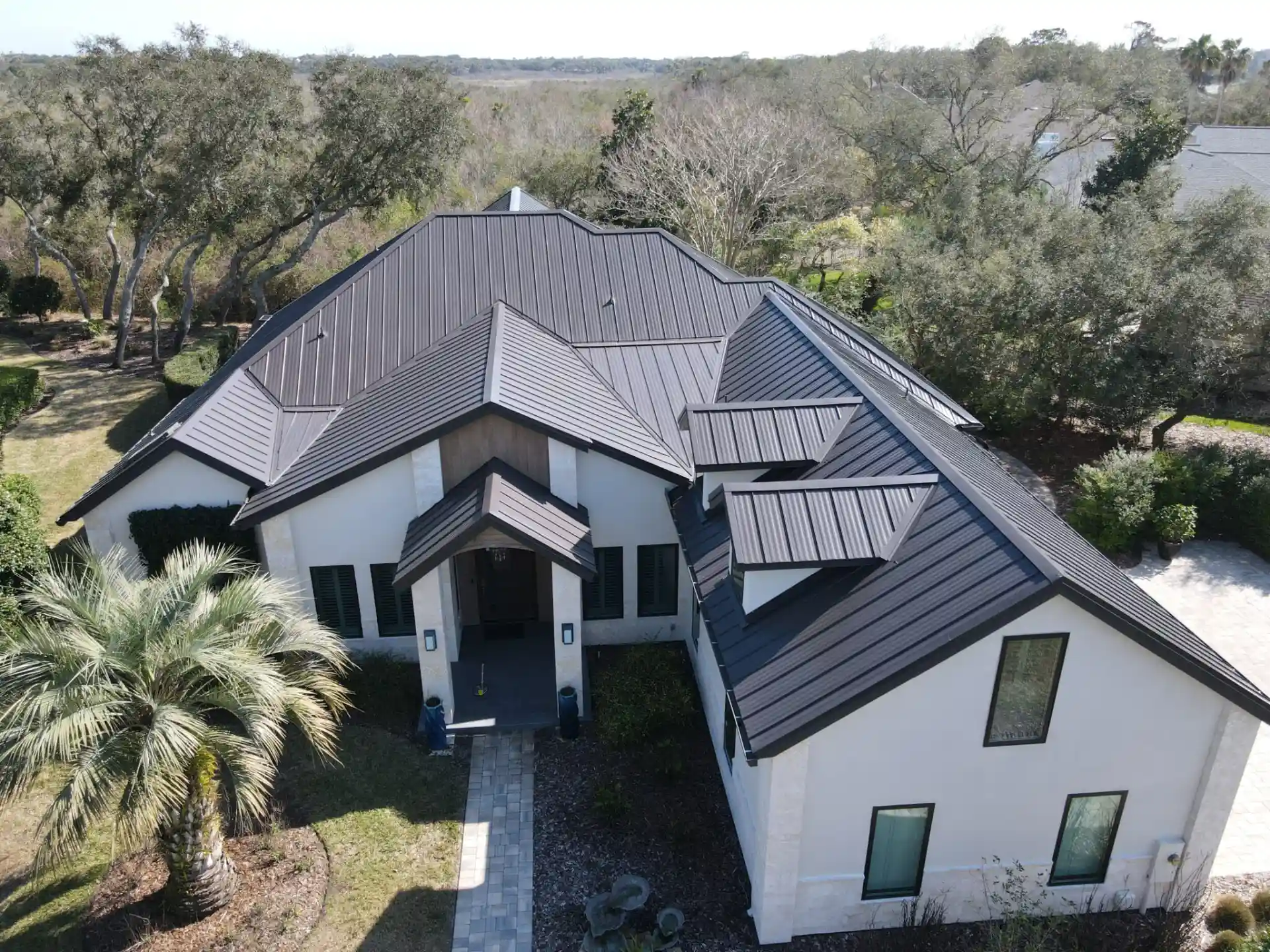 Aerial view of a brown metal roof on a tan home installed by Roofing Contractors In Fernandina Beach, FL | Universal Roof and Contracting