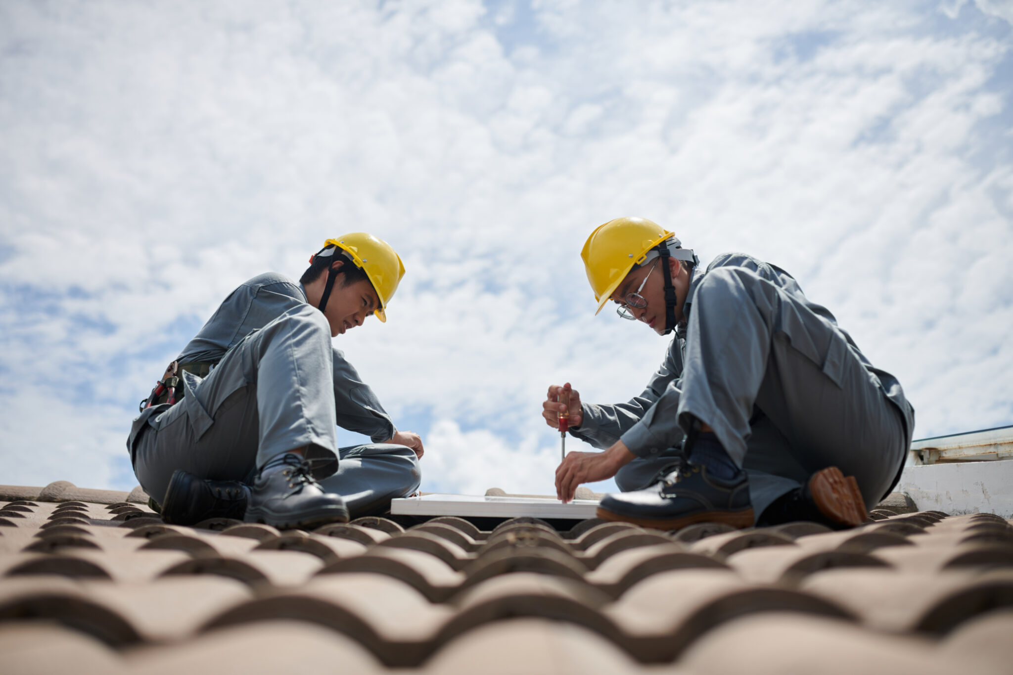 A pair of roofers carefully repair a Spanish tile roof in Central Florida.