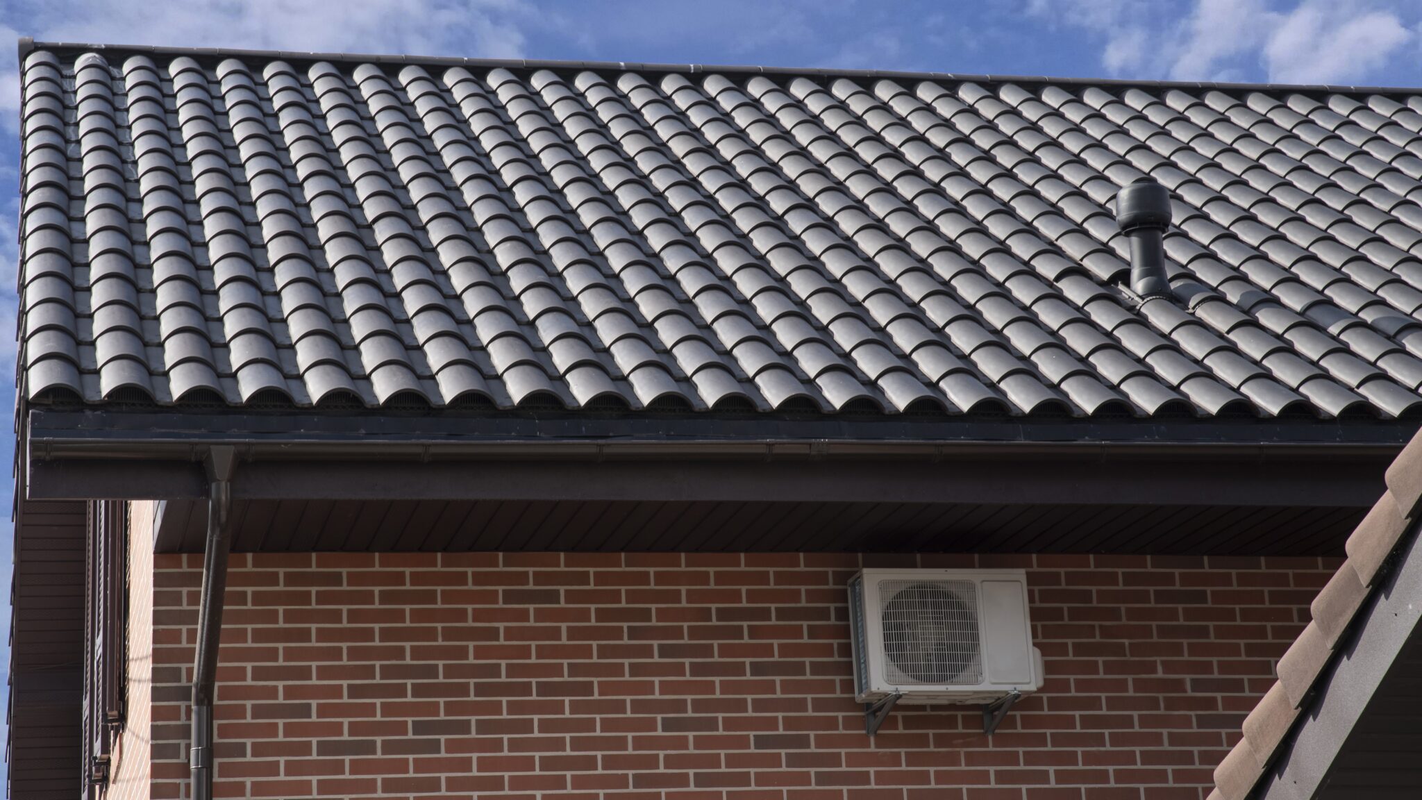 Home with dark black metal roofing tiles and classic brick siding