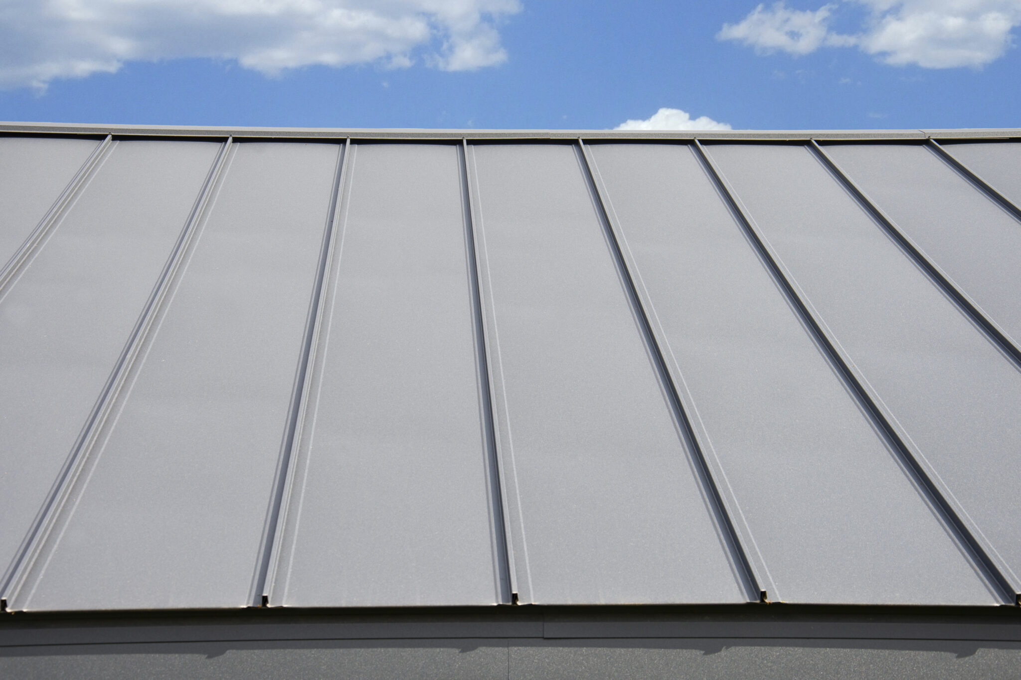 Close-up view of black metal roof against blue sky