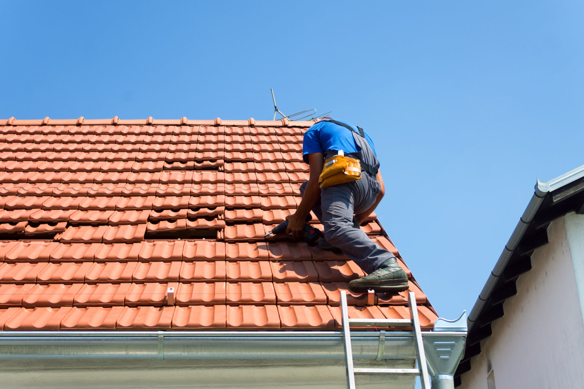 Roofer repairing a tile roof on a house