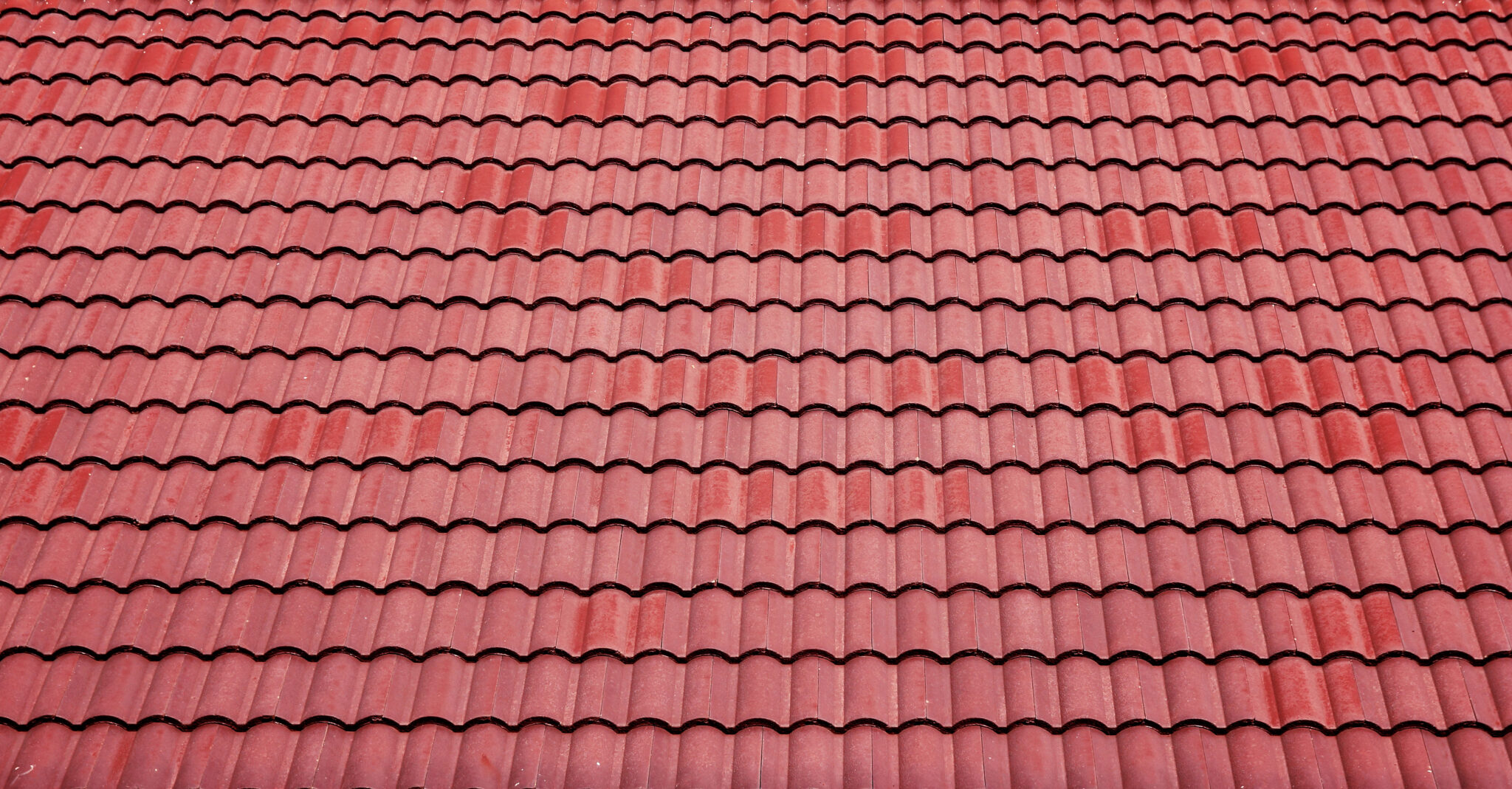 A close-up of a textured, wave-like, red, Spanish-style tile roof