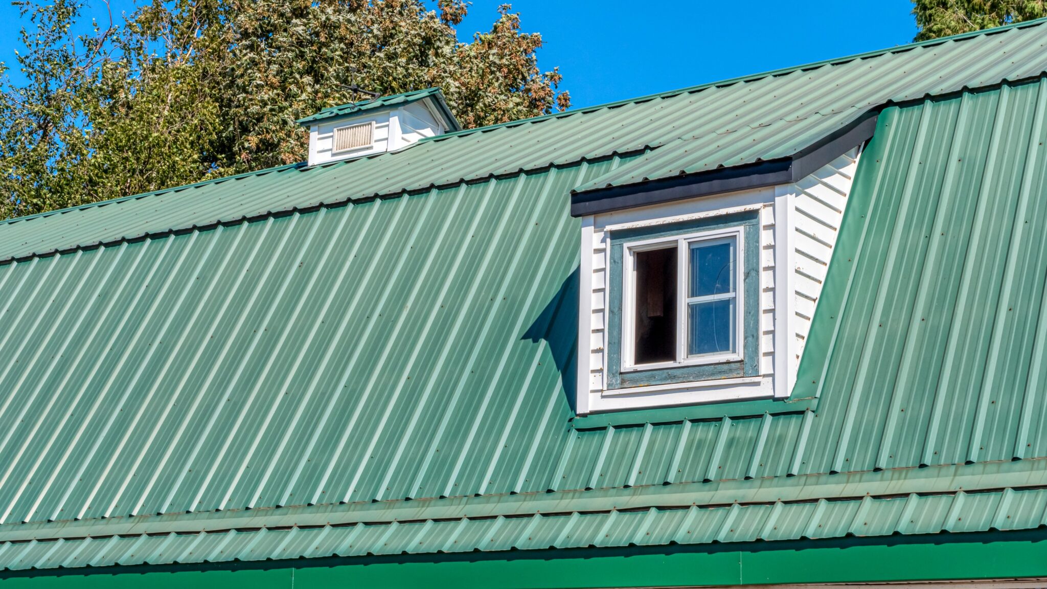 Home with large green metal roofing with large slope and small roof window
