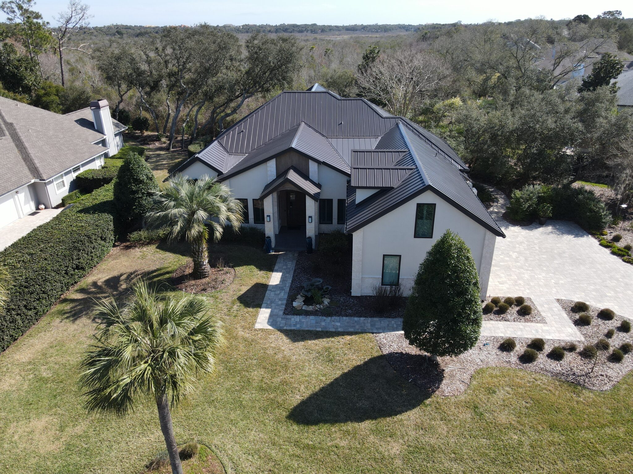 A Central Florida home with a beautiful dark metal roof that complements white walls and minimalist landscaping.