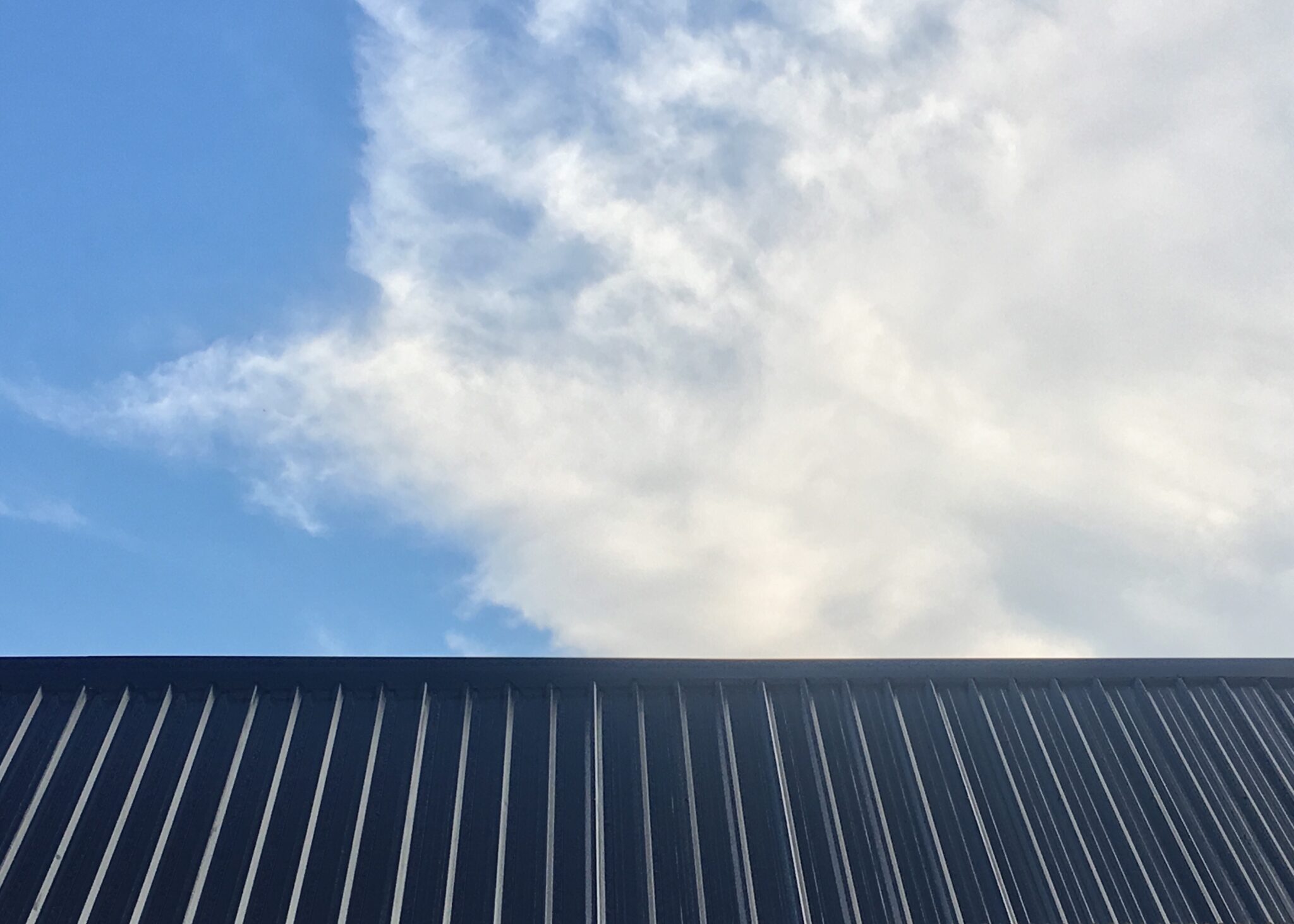 Metal roof against backdrop of blue sky turning cloudy