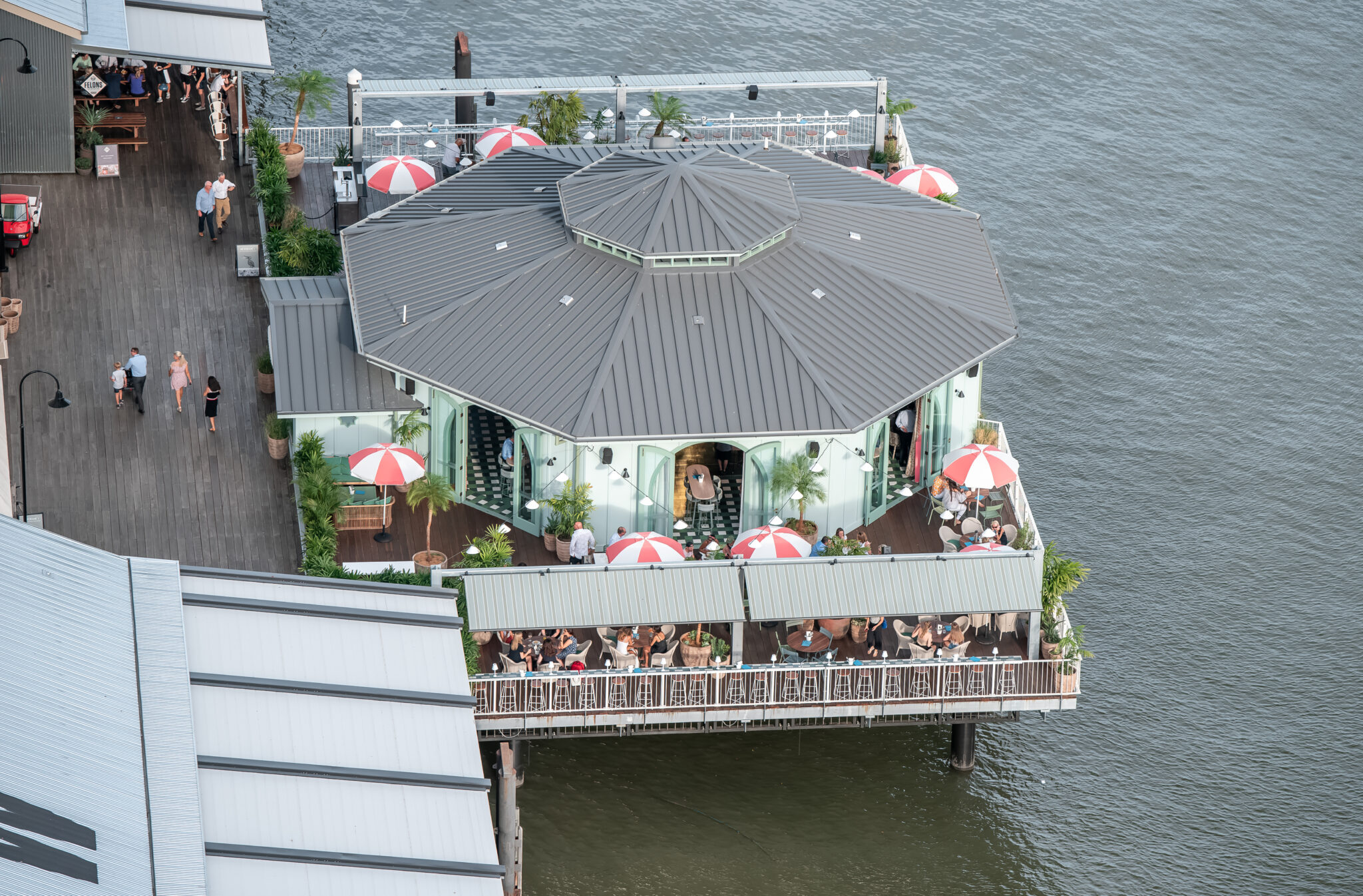 An overhead view of a bustling restaurant on a boardwalk with an octagonal metal roof.