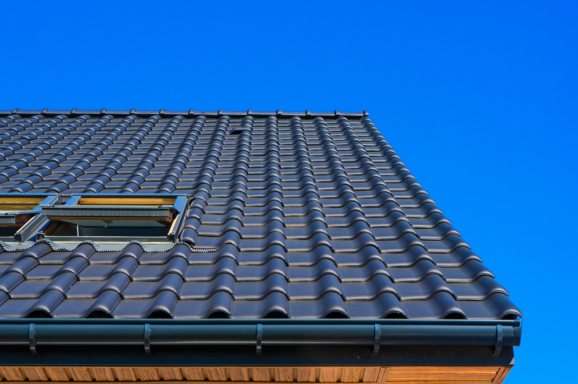 A black roof with unique tiles and an open skylight.